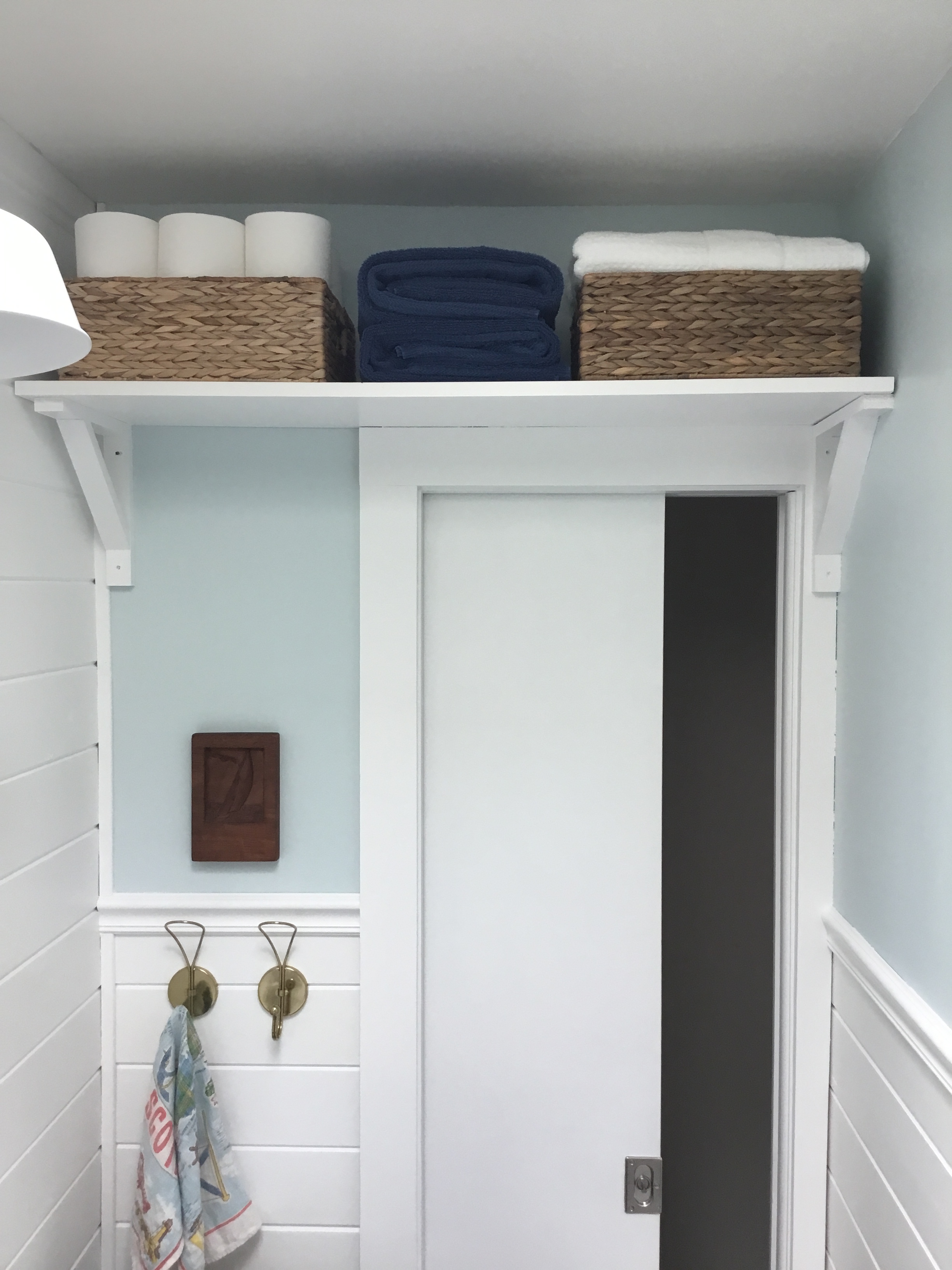 DIY towel and storage shelf above sliding bathroom door